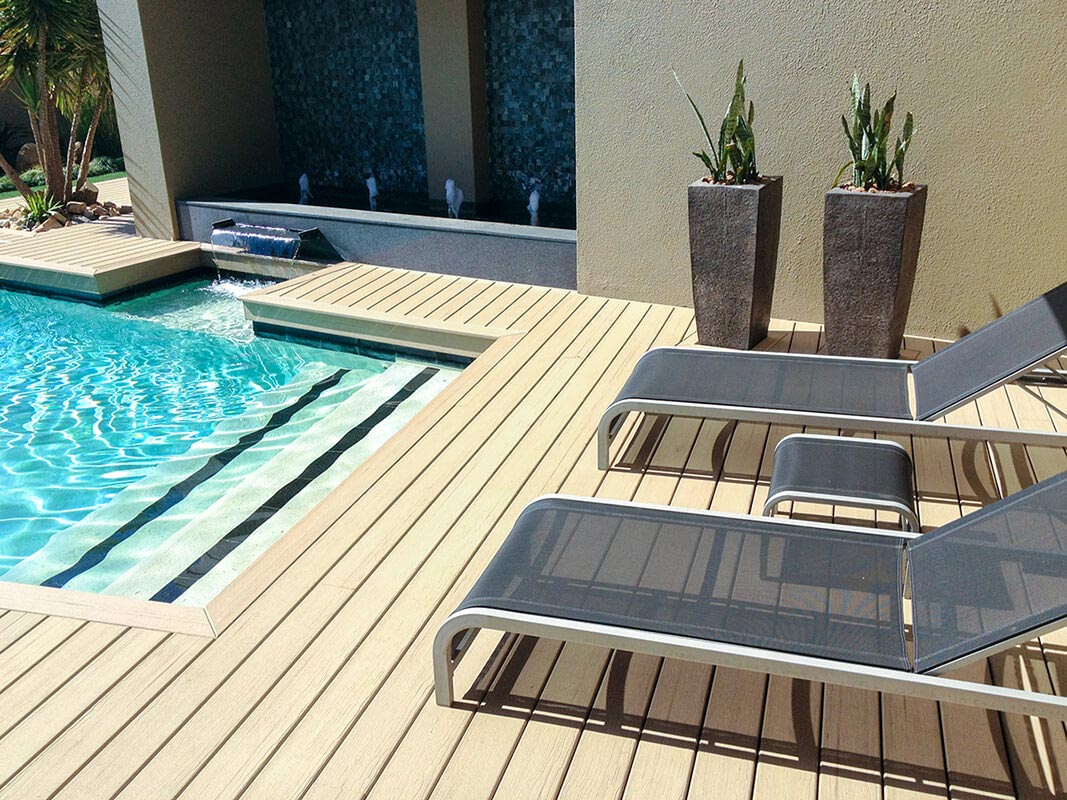 MoistureShield composite pool deck with deck chairs, tall planters, and a wall fountain.